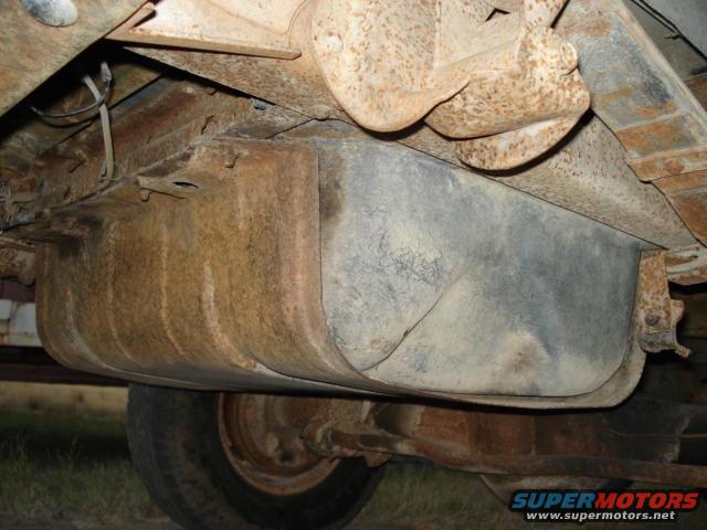 Undercarriage view showing a fuel tank, leaf springs, and part of a wheel