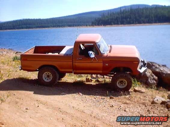 Orange pickup truck parked by a lake, lifted suspension, off-road tires
