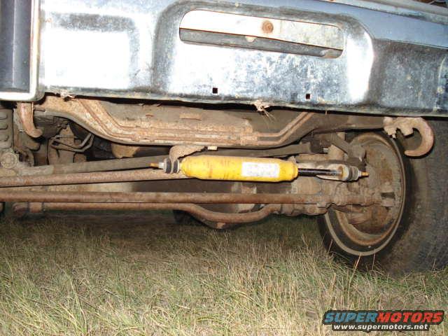Undercarriage view of a vehicle's suspension with a yellow shock absorber