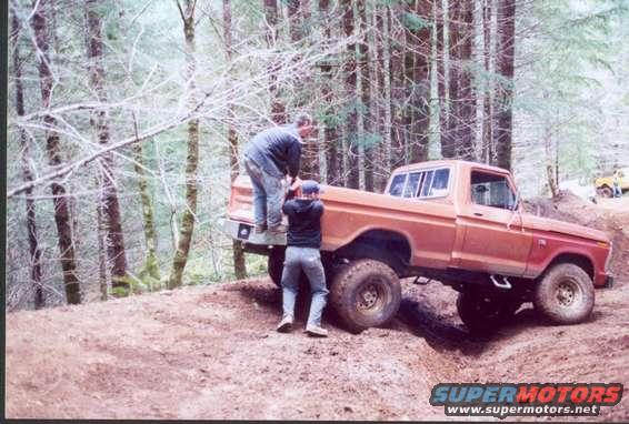 Orange pickup truck with two people in a wooded area