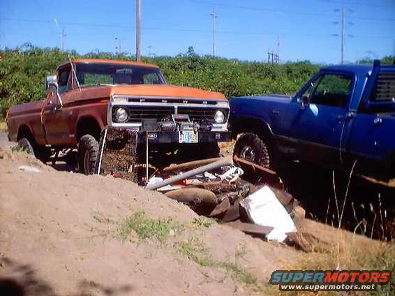 Orange pickup truck with winch and blue truck behind it