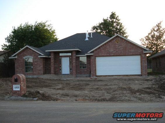 Brick house with white garage door and mailbox showing '4909'
