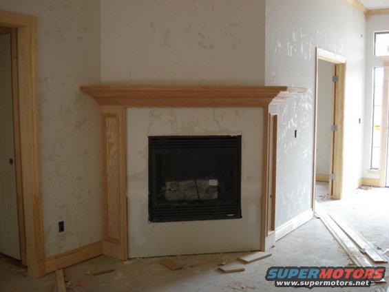fireplace with wood trim, unfinished walls, and doorway