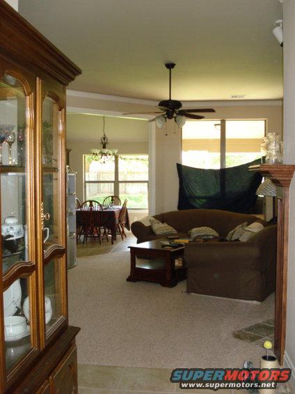 Interior view of a living room with brown couches and a coffee table, adjacent to a dining room with a table and chairs