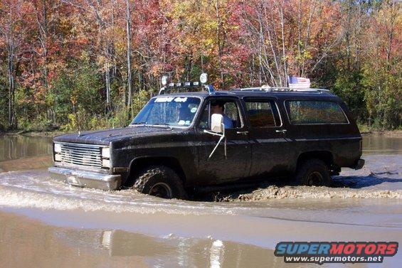 Black SUV with roof lights driving through mud; "Friday 4x4" sticker on windshield