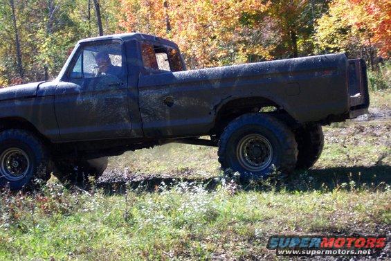 Mud-covered pickup truck with lifted suspension driving off-road