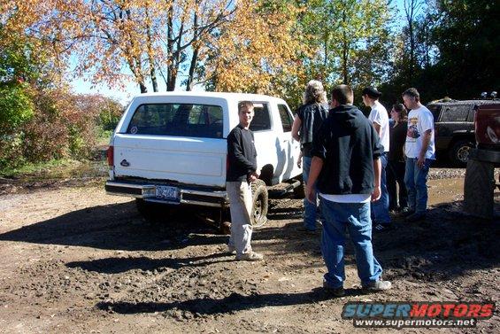 White SUV rear view with people around it. License plate visible
