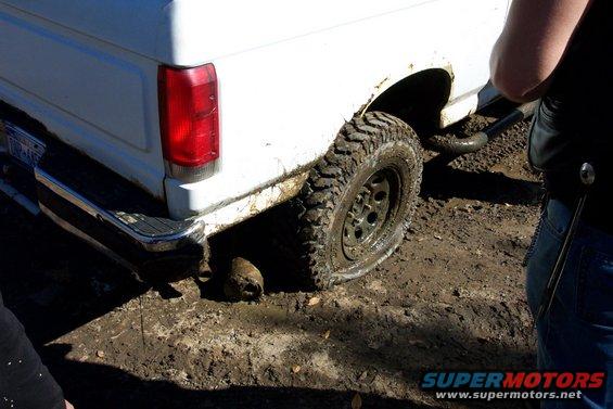 White vehicle's rear tire and fender, partially obscured