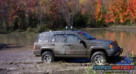 SUV parked on a dirt road with trees in the background