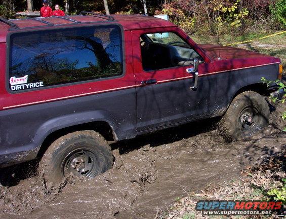 Red and blue 4x4 stuck in mud, side view