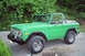 1975 Ford Bronco - A bright green 1975 Ford Bronco is shown from a three-quarter front angle, parked outdoors.