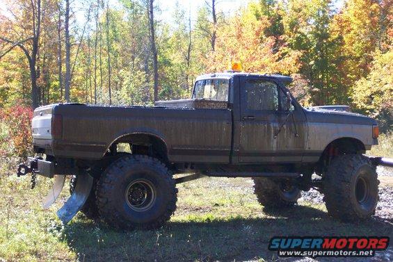 Side view of a lifted pickup truck with large tires and a plow attachment