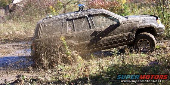 Muddy Jeep Grand Cherokee stuck in a muddy ditch with water splashing
