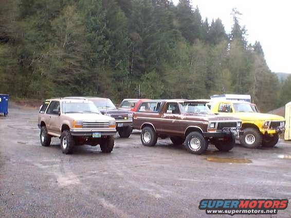 Tan Ford Explorer and brown Ford Bronco parked next to a yellow Ford pickup truck