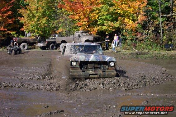 Mud-splattered 1979 pickup truck driving through mud pit