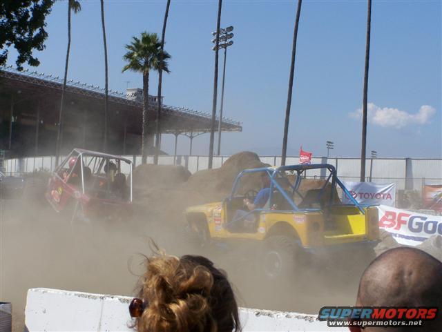 Yellow off-road buggy kicks up dust, with red buggy behind. Toyota and BFGoodrich banners visible
