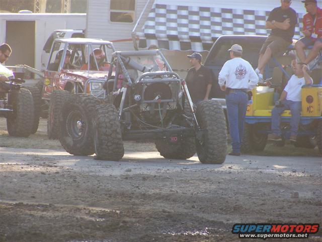Off-road buggy with large tires and exposed engine, viewed from the front