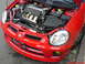 2005 Dodge SRT-4 - The engine bay of a red 2005 Dodge SRT-4 is visible with the hood open, revealing the engine and front end.