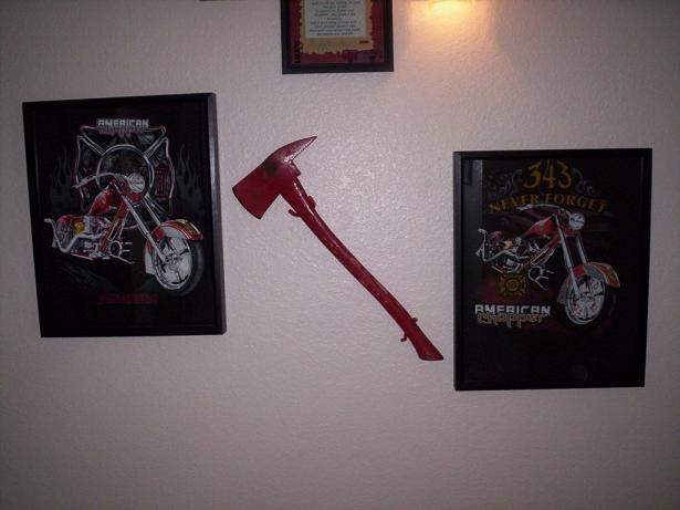 Red firefighter's axe mounted on wall between two framed prints of custom choppers