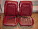 1979 Ford Bronco - Two red bucket seats, likely from an older vehicle, show significant wear and tear on the upholstery.