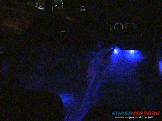 interior of a vehicle with blue underglow lighting and dashboard lights visible