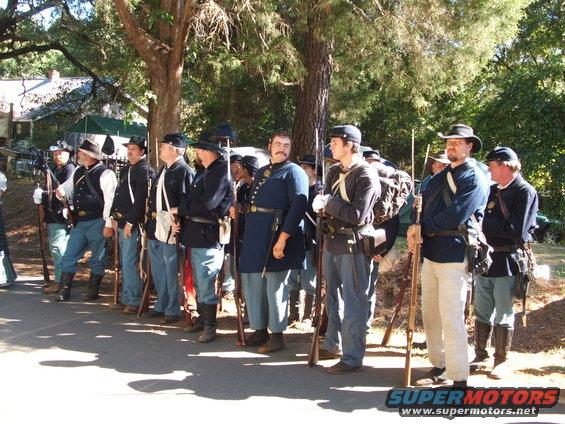 Group of men in Civil War era uniforms standing in formation with rifles