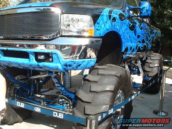 Monster truck with blue flame graphics and DUB branding on suspension components