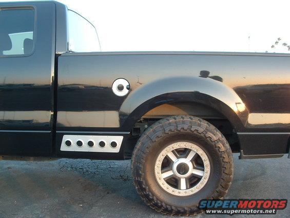 Black pickup truck side view showing fuel door, fender, and wheel