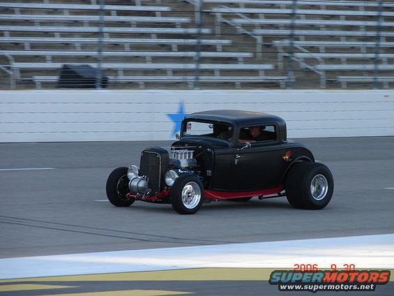 black hot rod coupe with exposed engine on a track