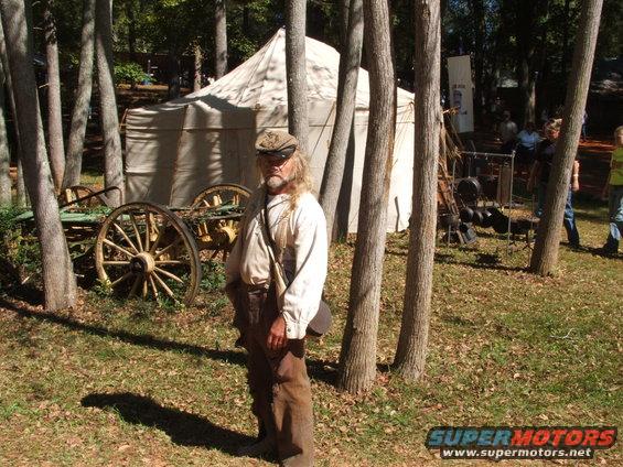 Man in historical reenactment attire, tent, and wagon