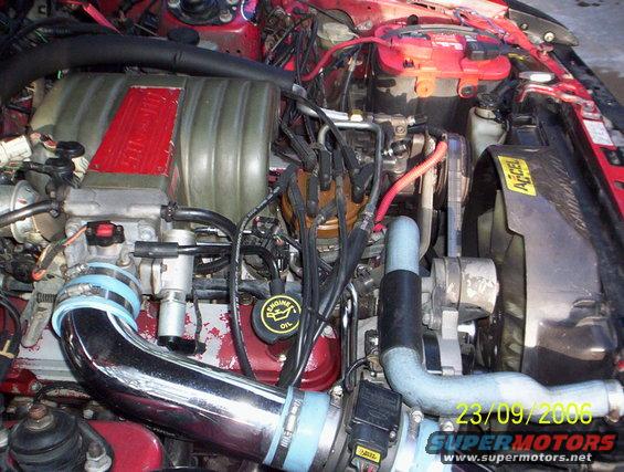 Engine bay with red intake manifold, chrome piping, and battery