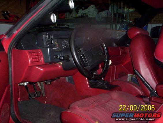 Red interior of a car, showing dashboard, steering wheel, and seats