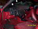 1990 Ford Mustang - The interior of a red car is visible, a black steering wheel and dashboard, along with red seats.