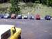 1976 Ford F-100 - A group of off-road vehicles are parked in a lot, with a wooded hillside behind them.