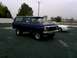 1978 Ford Bronco - A dark blue 1978 Ford Bronco is parked on a gravel lot under an overcast sky.