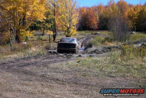 Truck stuck in a muddy rut with fall foliage in the background
