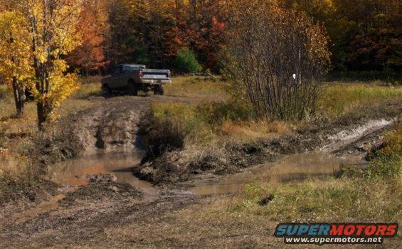 Pickup truck driving through mud and water on an off-road trail during autumn