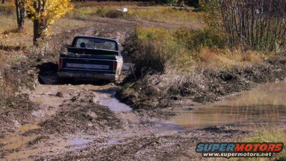 Dark blue Ford F-Series truck navigating a muddy trail