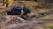 1979 Ford Bronco - A Ford F-Series truck drives through a muddy, off-road path.
