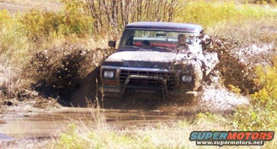 Ford Bronco stuck in mud, front view. Grille suggests 1978 model year