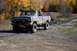 1979 Ford Bronco - A lifted, mud-covered Ford pickup truck navigates a wet, off-road trail during autumn.