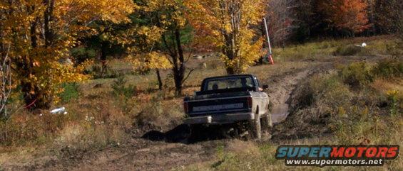 1979 Ford Bronco driving on a muddy trail with fall foliage