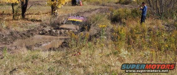 Purple off-road vehicle with 'SMUGGER' text stuck in mud