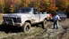1979 Ford Bronco - A muddy 1979 Ford F-150 pickup truck is stuck in the mud with other vehicles and people nearby.