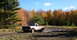 1979 Ford Bronco - A white pickup truck is stuck in a muddy area with fall foliage visible behind it.