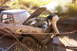 1979 Ford Bronco - A person inspects the engine of a mud-splattered pickup truck stuck in a muddy ditch.