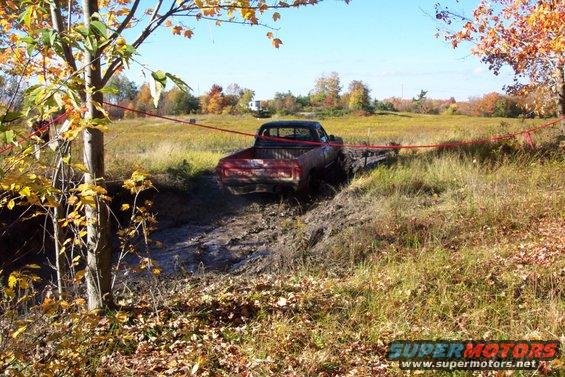 Red pickup truck stuck in mud, rear view