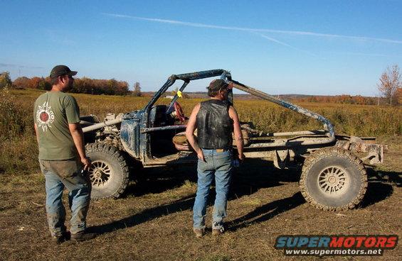 Two guys stand next to a custom buggy with a roll cage and no body panels