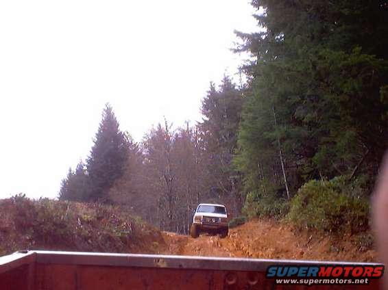 White 1976 Ford F-100 driving on a dirt road