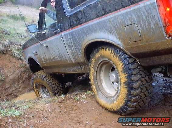 Side view of a mud-covered 1976 Ford F-100 driving off-road